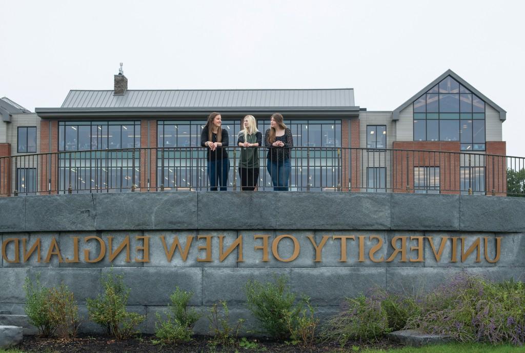 Davis Scholars attending U N E stand on the walkway above the University of New England lettering on the Biddeford Campus