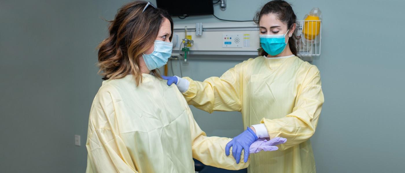 Two U N E students in surgical clothes work together